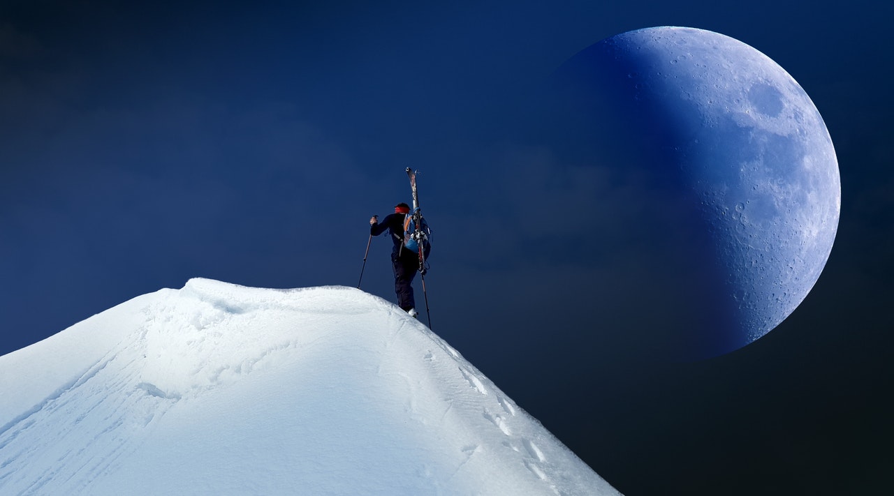 Person climbs snowy mountain towards the summit