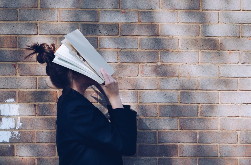 student holding book to her face