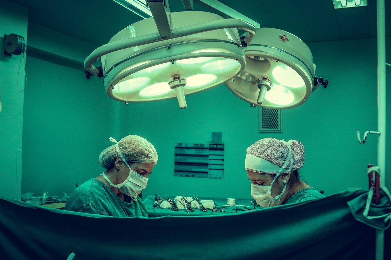 two surgeons operating behind drape; green colored