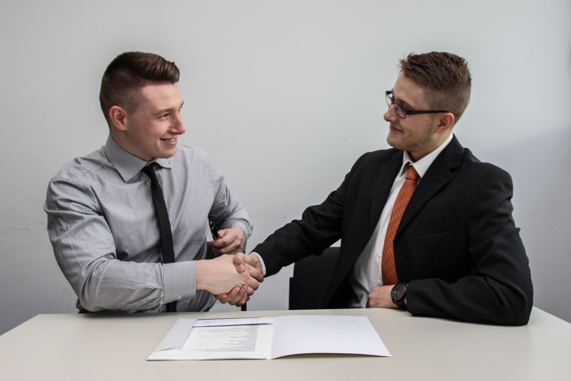 two men at table shaking hands