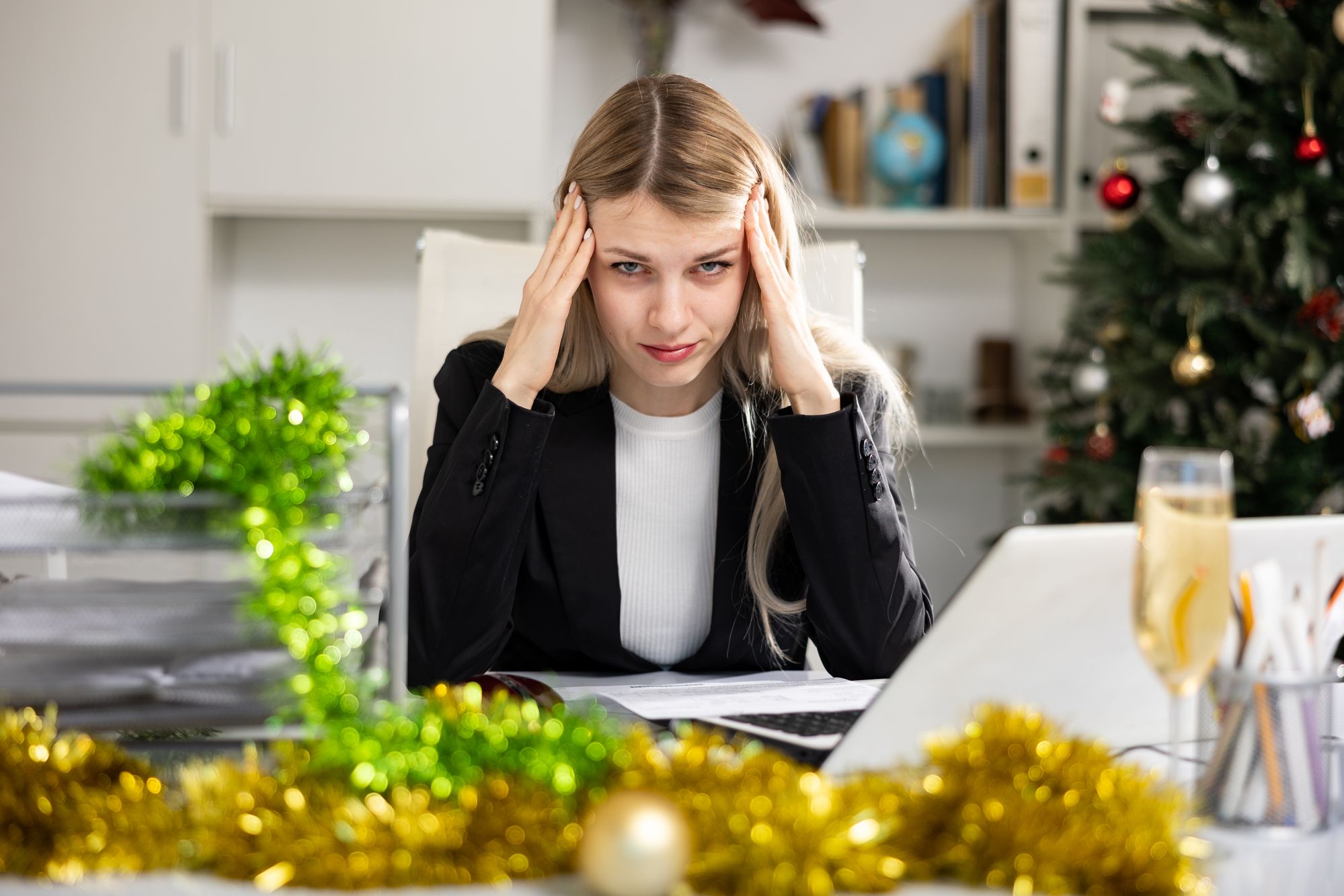 Holiday stress - girl working with hands on her head, Christmas decorations in the background