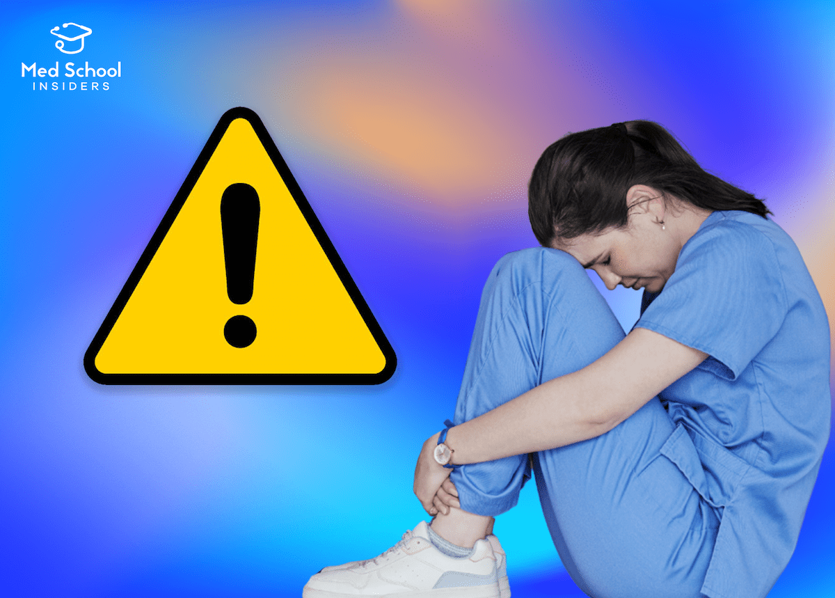 Unhappy medical student sitting on the ground next to a warning sign