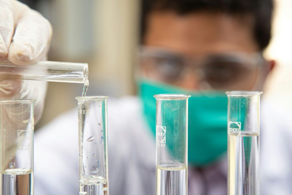 medical scientist - pouring clear liquid in test tubes