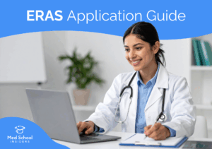 Medical student in a white coat using a laptop and taking notes while preparing a residency application through ERAS.