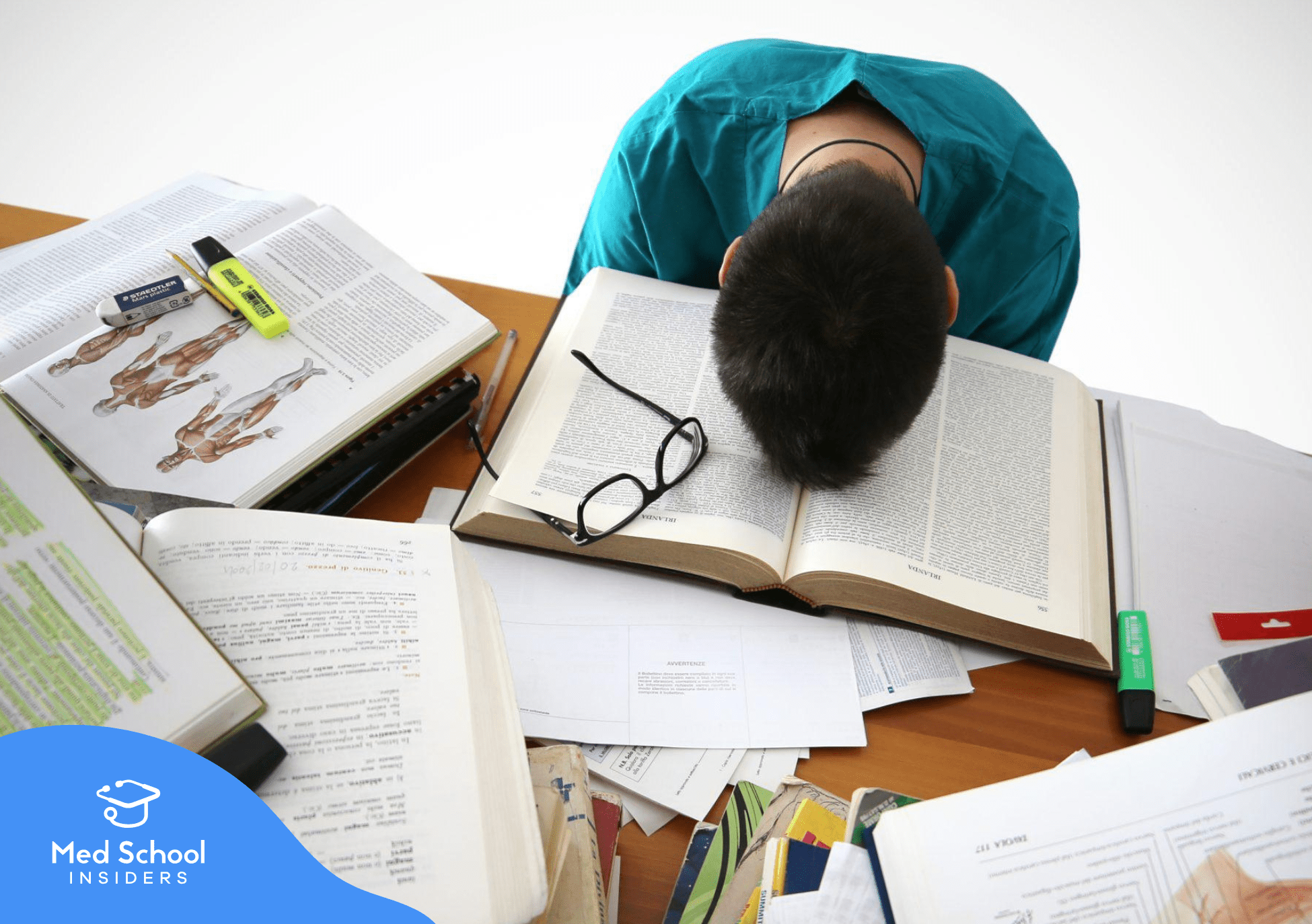 Stressed premed student with their face buried in an open book, studying at a desk, representing burnout and common mistakes when reapplying to medical school.